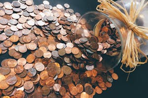 Spilled jar of pennies creating a pattern of coins representing savings and finance.